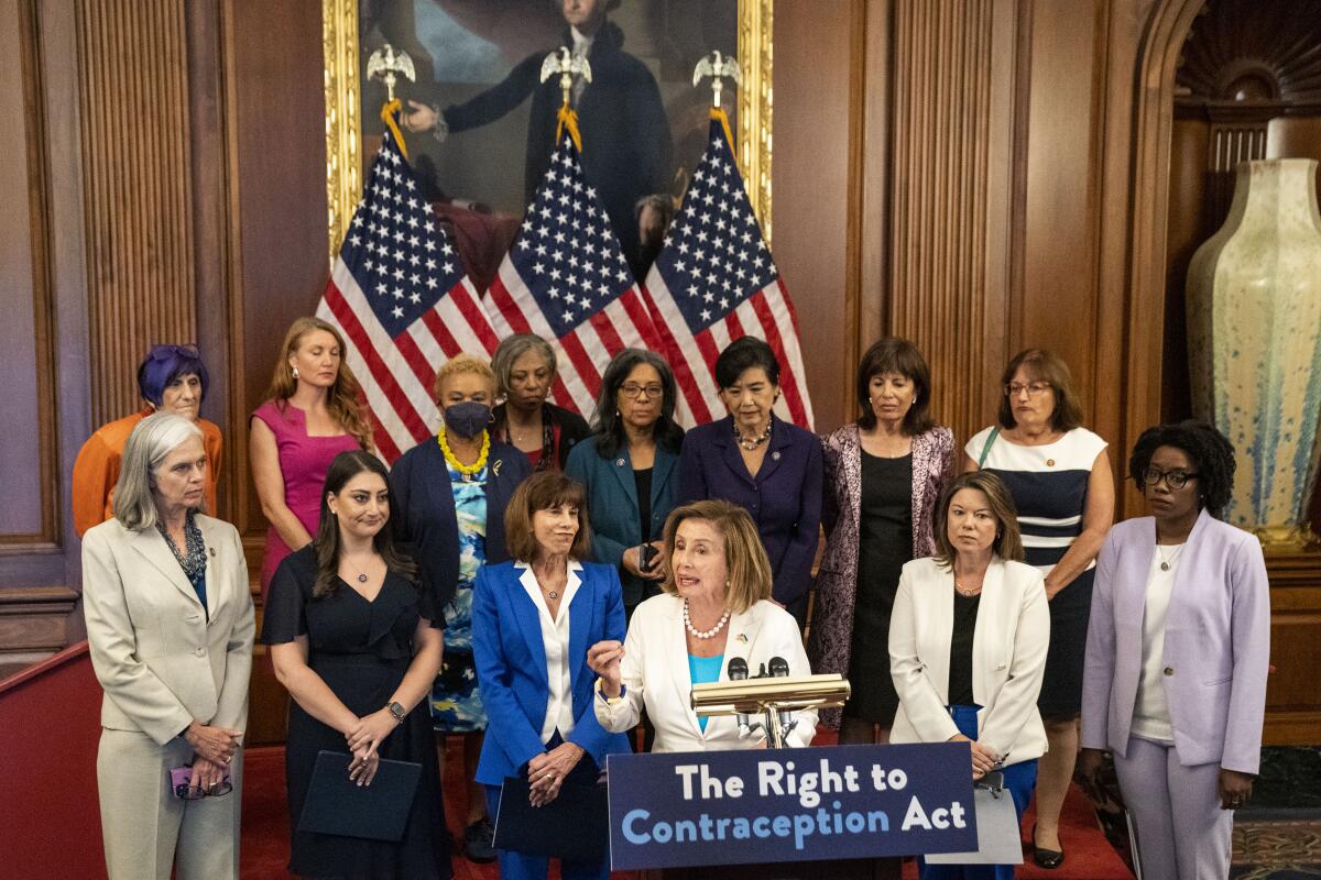 House Speaker Nancy Pelosi speaks at a podium surrounded by other women