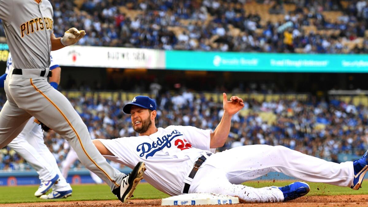 Dodgers pitcher Clayton Kershaw hangs on to the ball as he tags out Bryan Reynolds of the Pittsburgh Pirates at first base in the second inning.