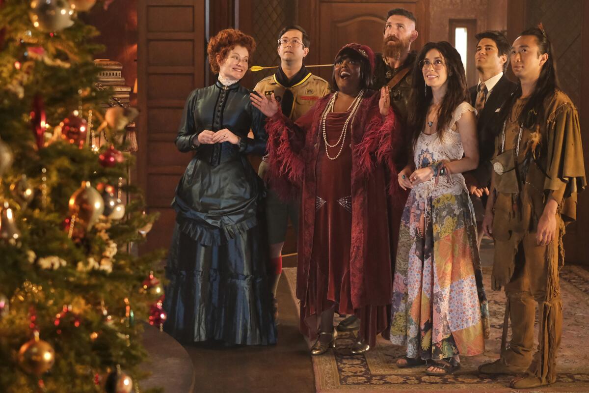 Cast members of the TV series ”Ghosts" standing near a Christmas tree.