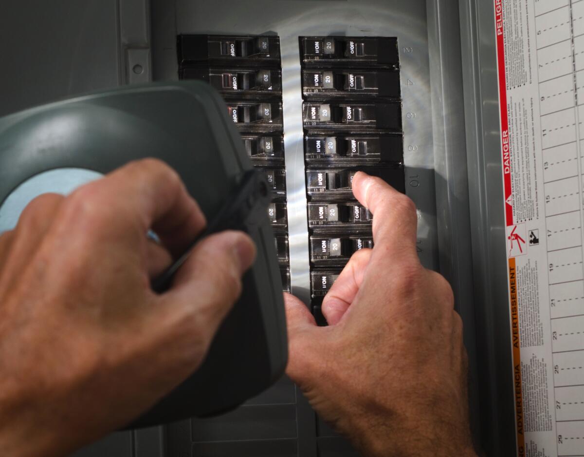 A man with a flashlight at a residential circuit breaker panel 