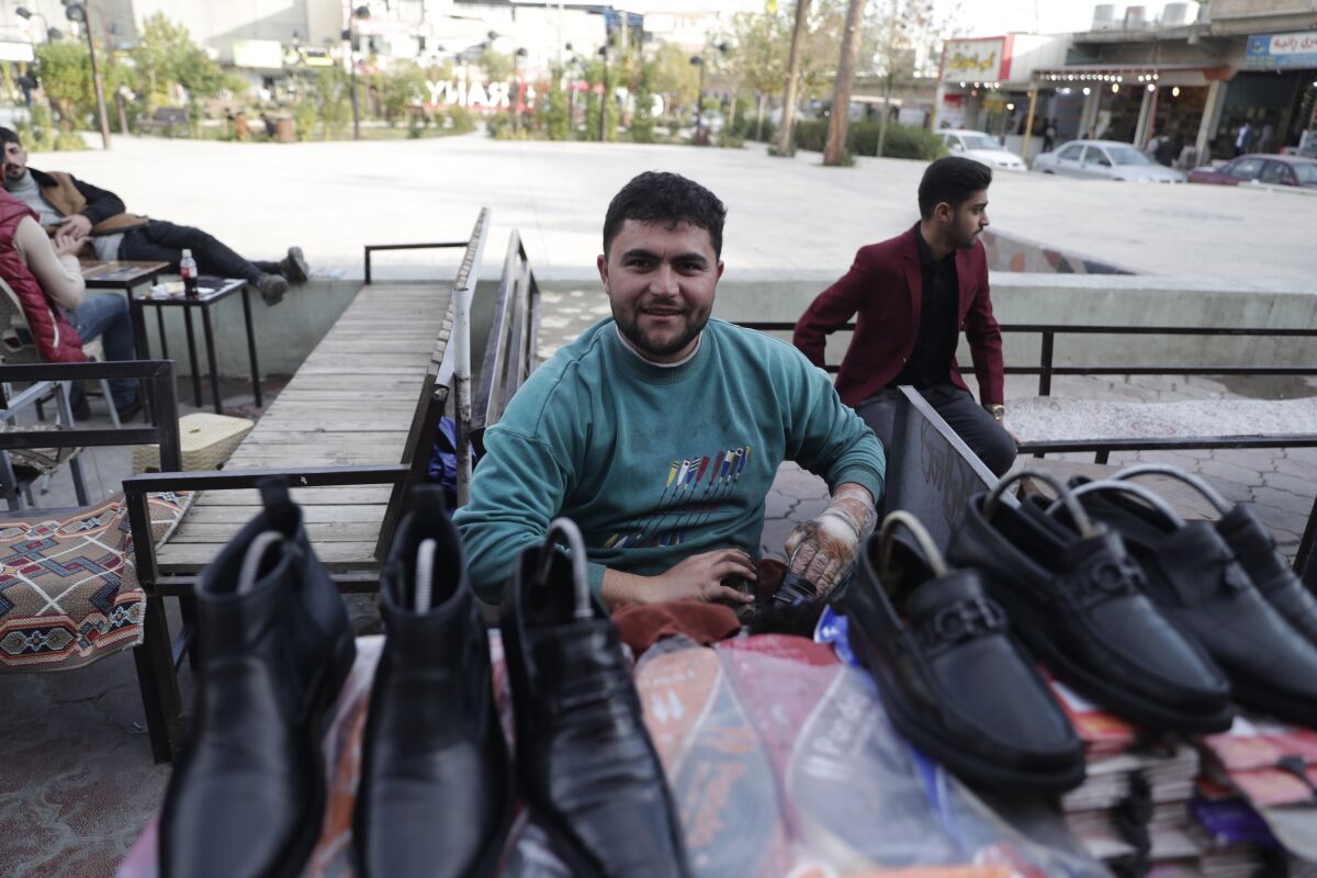 Mohammad Bert, a former student who dropped out and works as a cobbler on the street to support his family at a park in Ranya, a town in the Kurdish-run region of Iraq, Tuesday, Nov. 30, 2021. Across universities in northern Iraq, the spectre of unemployment haunts both students and teachers. Many speak of growing empty seats in classrooms; students who had left for Europe. (AP Photo/Khalid Mohammed)