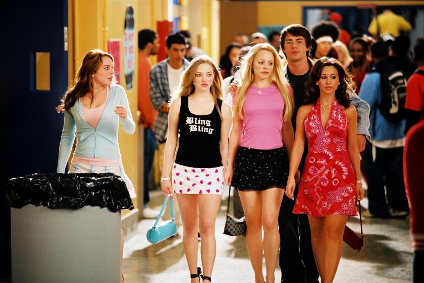 Mean Girls Amanda Seyfried, Rachel McAdams, Lacey Chabert walk in a tight row down school hallway next to Lindsay Lohan