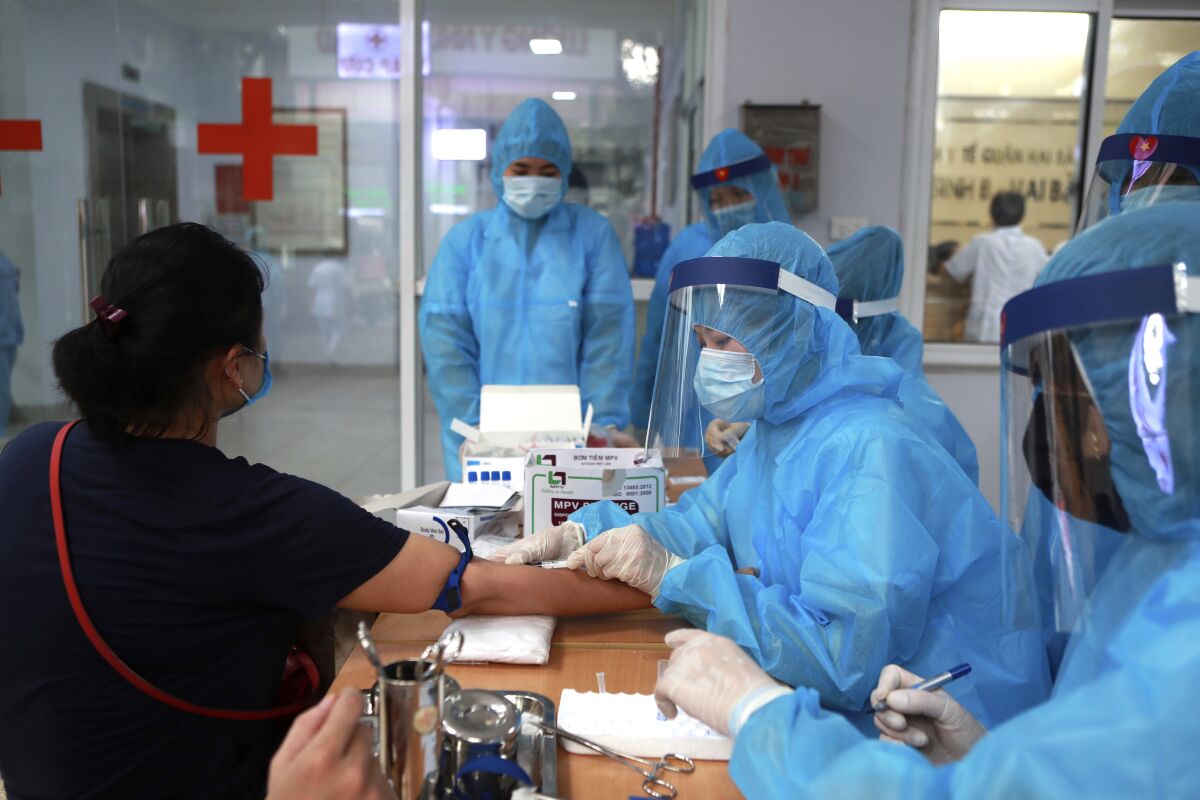 A health worker draws blood for COVID-19 test in Hanoi, Vietnam on Friday, July 31, 2020. Vietnamese state media on Friday reported the country's first-ever death of a person with the coronavirus as it struggles with a renewed outbreak after 99 days without any cases. (AP Photo/Hau Dinh)