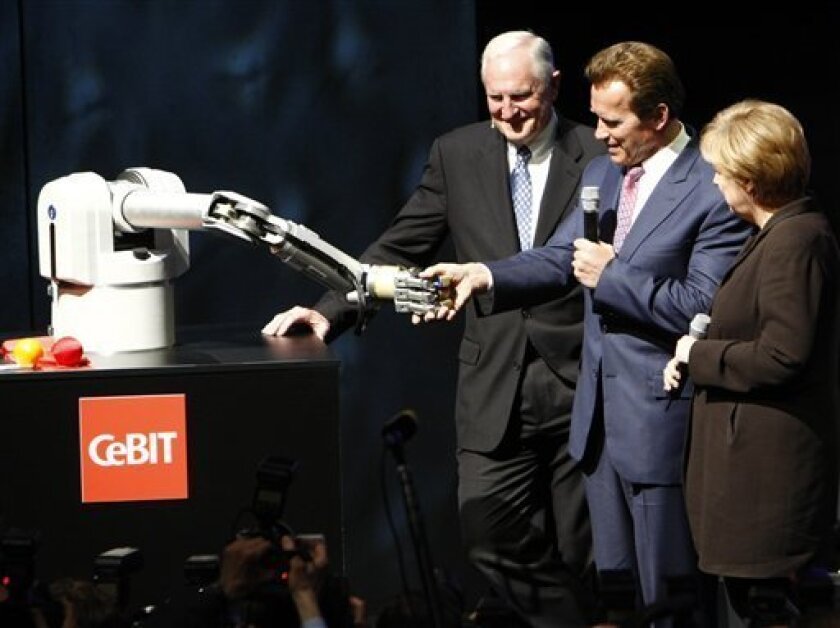 Arnold Schwarzenegger, Governor of California, center, shakes hands with robotic arm 'Marvin' during the opening ceremony of the CeBIT in Hanover, northern Germany, on Monday, March 2, 2009. Craig R. Barrett, chairman of the board of Intel, left, and German Chancellor Angela Merkel, right, watch him. California is partner state of the CeBIT 2009.(AP Photo/Joerg Sarbach)