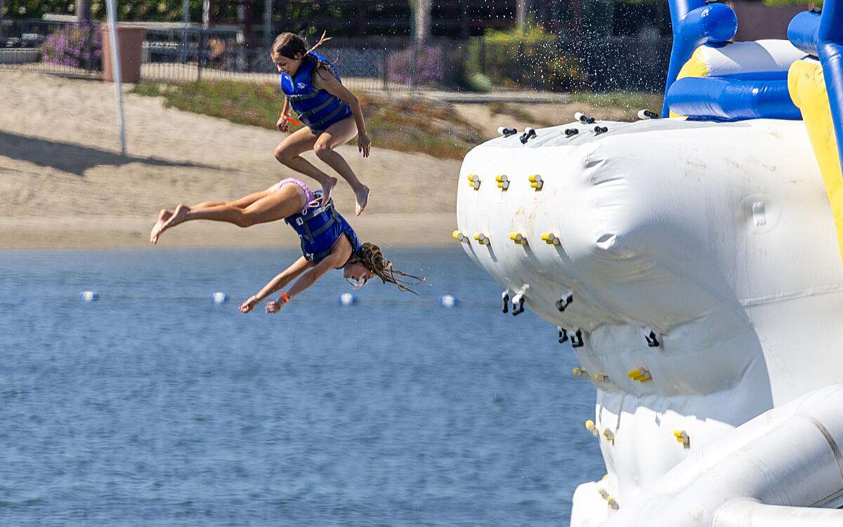 Kids have fun jumping off one of 30 oversized inflatables in the Inflatable Aquatic Park on a sunny, warm day.