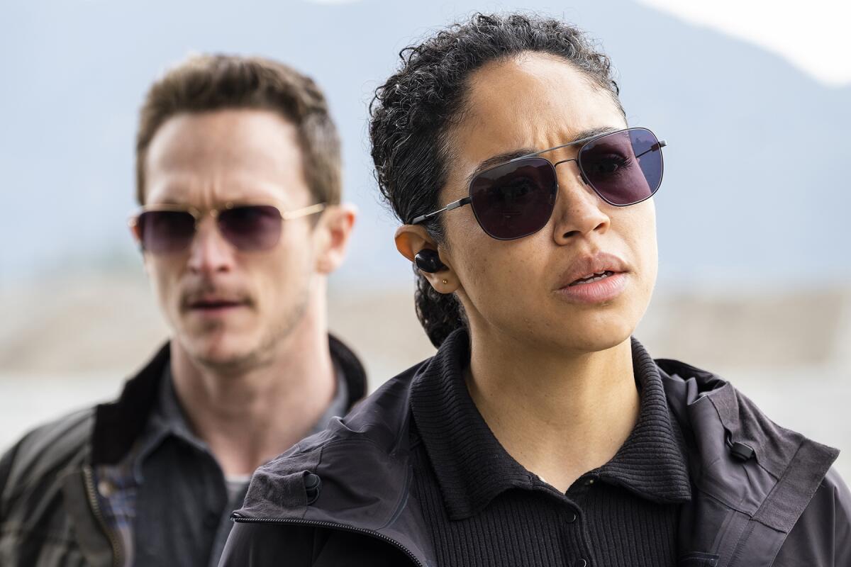A man and a woman both wearing dark glasses and clothing