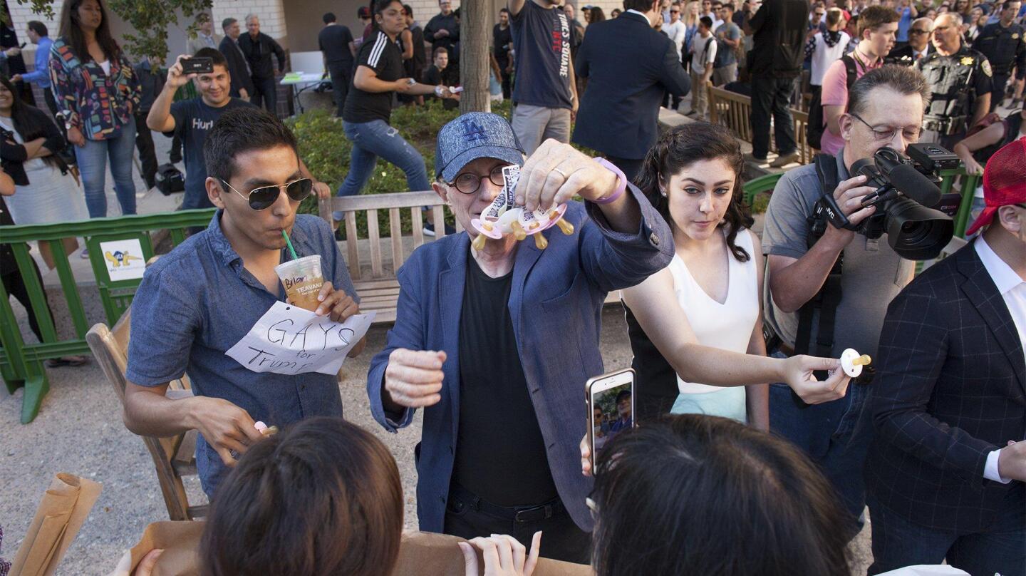 Members of College Republicans at UCI hand out pacifiers to protesters before an event featuring speaker Milo Yiannopoulos at UC Irvine on Thursday.