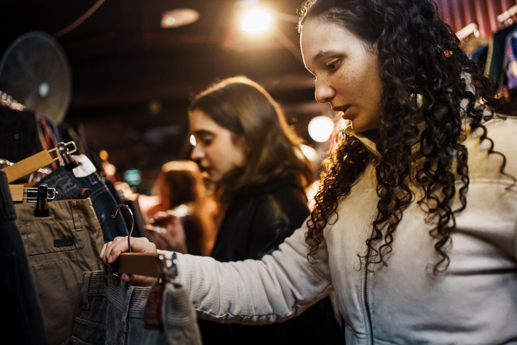 Two teen girls shop for clothes at a second-hand fair