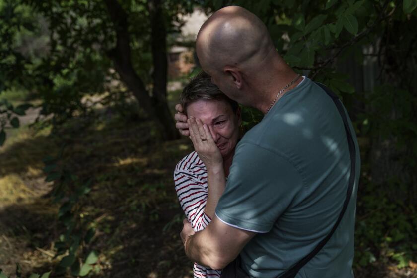 CORRECTS SPELLING TO VADIM NOT VADIN Marina Havrysh, left, is comforted by her husband, Vadim, as she weeps while watching her elderly parents helped into a van to be evacuated to a safer part of the country in the west from their home in Kramatorsk, Donetsk region, eastern Ukraine, Tuesday, Aug. 2, 2022. "I understand that this will be the last time I ever see them," she said. "You see their age, I can't give them the proper care." (AP Photo/David Goldman)