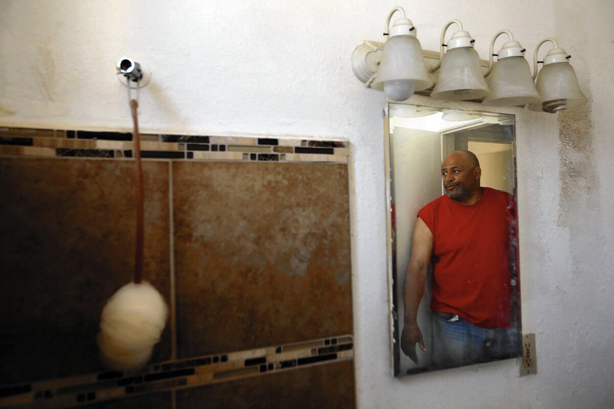Bruce Smith, reflected in the mirror, looks over his bathroom that doesn't have a shower head or faucet. The Long Beach apartment, which he had been living in for two years with Larry Watson, had no running water. It was gutted by a fire Wednesday morning.
