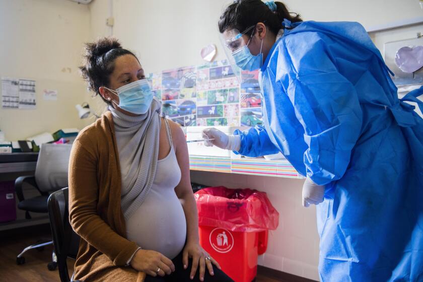 A nurse gives a shot of the Pfizer vaccine for COVID-19 to a pregnant woman.