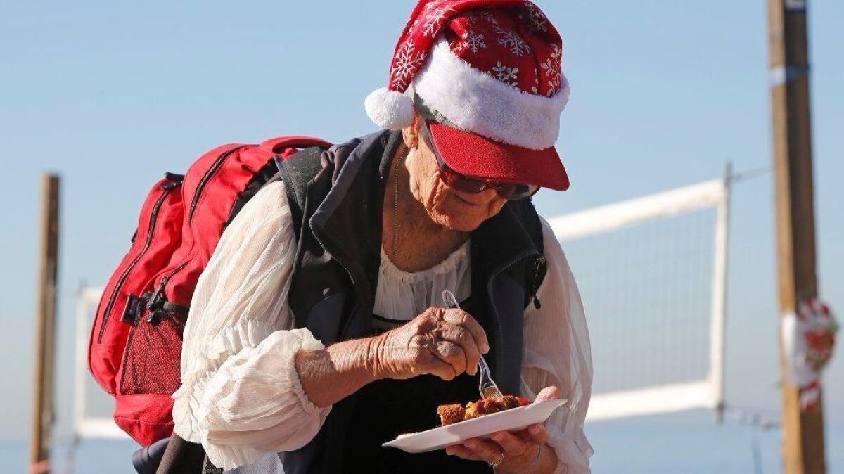 A woman in a holiday hat enjoys Trish and Brad Miller's outreach breakfast at Laguna's Main Beach on Dec. 13.