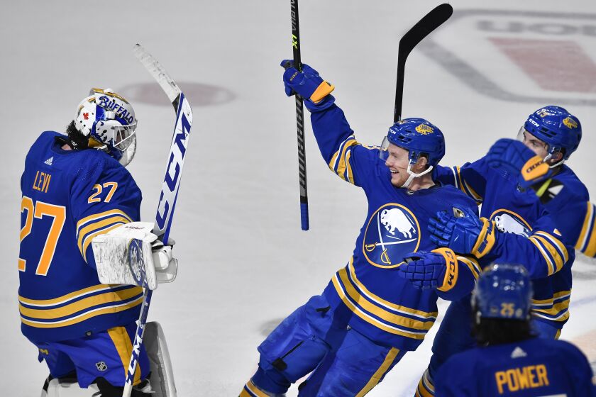 Buffalo Sabres left wing Jeff Skinner, center, celebrates with goalie Devon Levi, left, after scoring against the New York Rangers in overtime of an NHL hockey game in Buffalo, N.Y., Friday, March 31, 2023. (AP Photo/Adrian Kraus)
