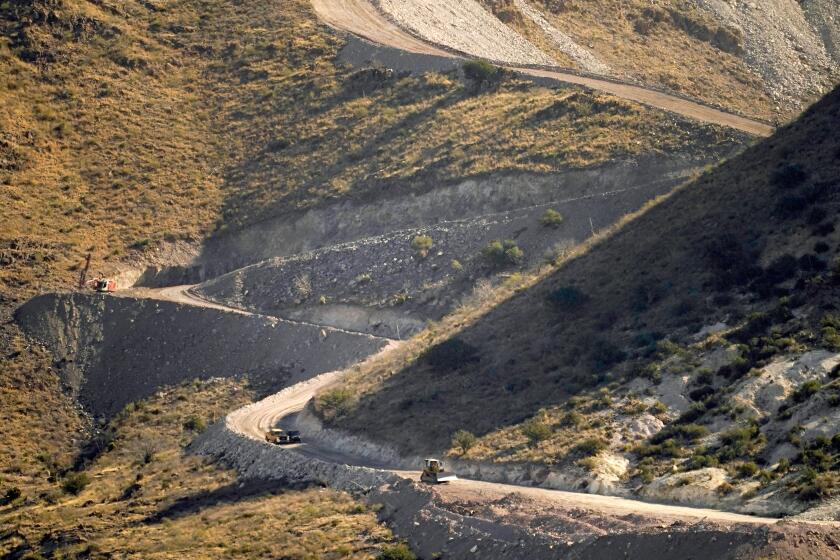 A pathway cleared by explosives to make way for border wall construction separates Mexico, right, and the USA, Wednesday, Dec. 9, 2020, in Guadalupe Canyon, Ariz. Construction of the border wall, mostly in government owned wildlife refuges and Indigenous territory, has led to environmental damage and the scarring of unique desert and mountain landscapes that conservationists fear could be irreversible. (AP Photo/Matt York)