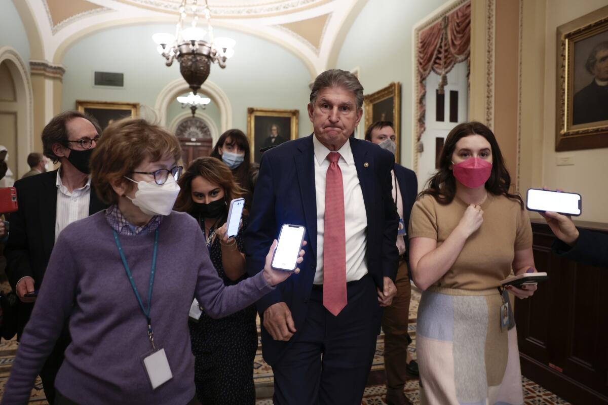 Sen. Joe Manchin III is followed by reporters after a caucus meeting.