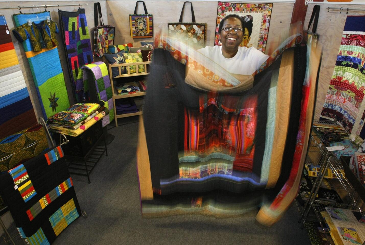 Patsy Johnson, 58, holds one of the many quilts that she designs, makes and sells at Crafted at the Port of Los Angeles. Johnson quit a 25-year career as an insurance broker, saying she was tired of corporate life.