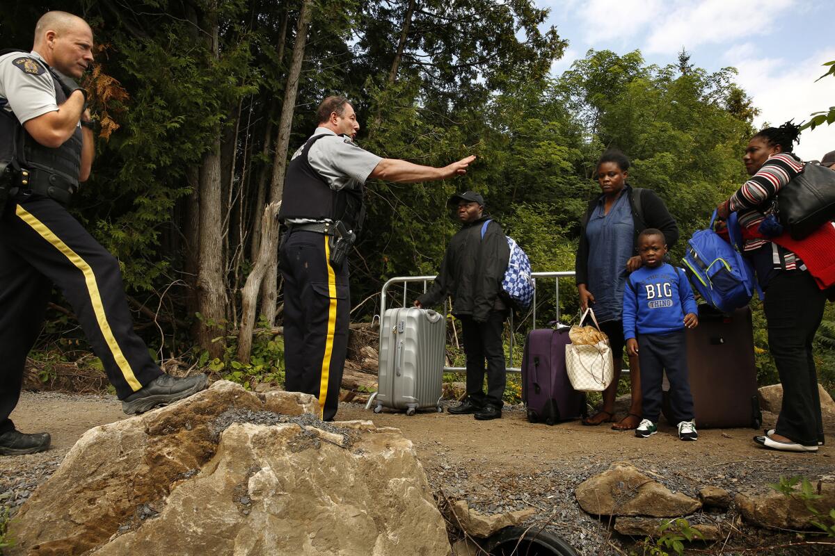 Sgt. Michael Harvey, center, of the Royal Canadian Mounted Police, stops a group of Haitians before they attempt to cross the border illegally. If they cross here, he tells them, they will be arrested. (Carolyn Cole / Los Angeles Times)