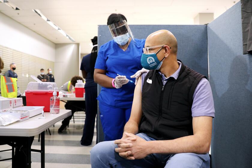 LOS ANGELES-CA-MARCH 11, 2021: Dr. Mark Ghaly, Secretary of the California Health and Human Services Agency, gets a one-dose Janssen COVID-19 vaccine by Johnson & Johnson by nurse LeShay Brown, during a media event hosted by The California Department of Public Health as part of the states efforts to increase vaccine acceptance among groups that are less likely to be vaccinated, and highlights California's efforts to equitably and efficiently administer COVID vaccines, at the Baldwin Hills Crenshaw Plaza in Los Angeles on Thursday, March 11, 2021. (Christina House / Los Angeles Times)