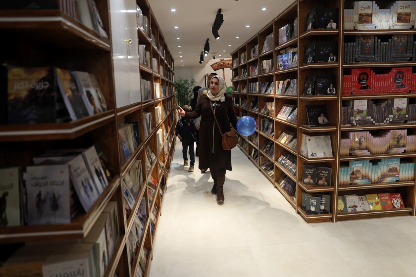 People browse bookshelves at the Samir Mansour Bookstore that was destroyed during Israel's war with Gaza's Hamas rulers last May, during the re-opening ceremony in Gaza City, Thursday, Feb. 17, 2022. (AP Photo/Adel Hana)