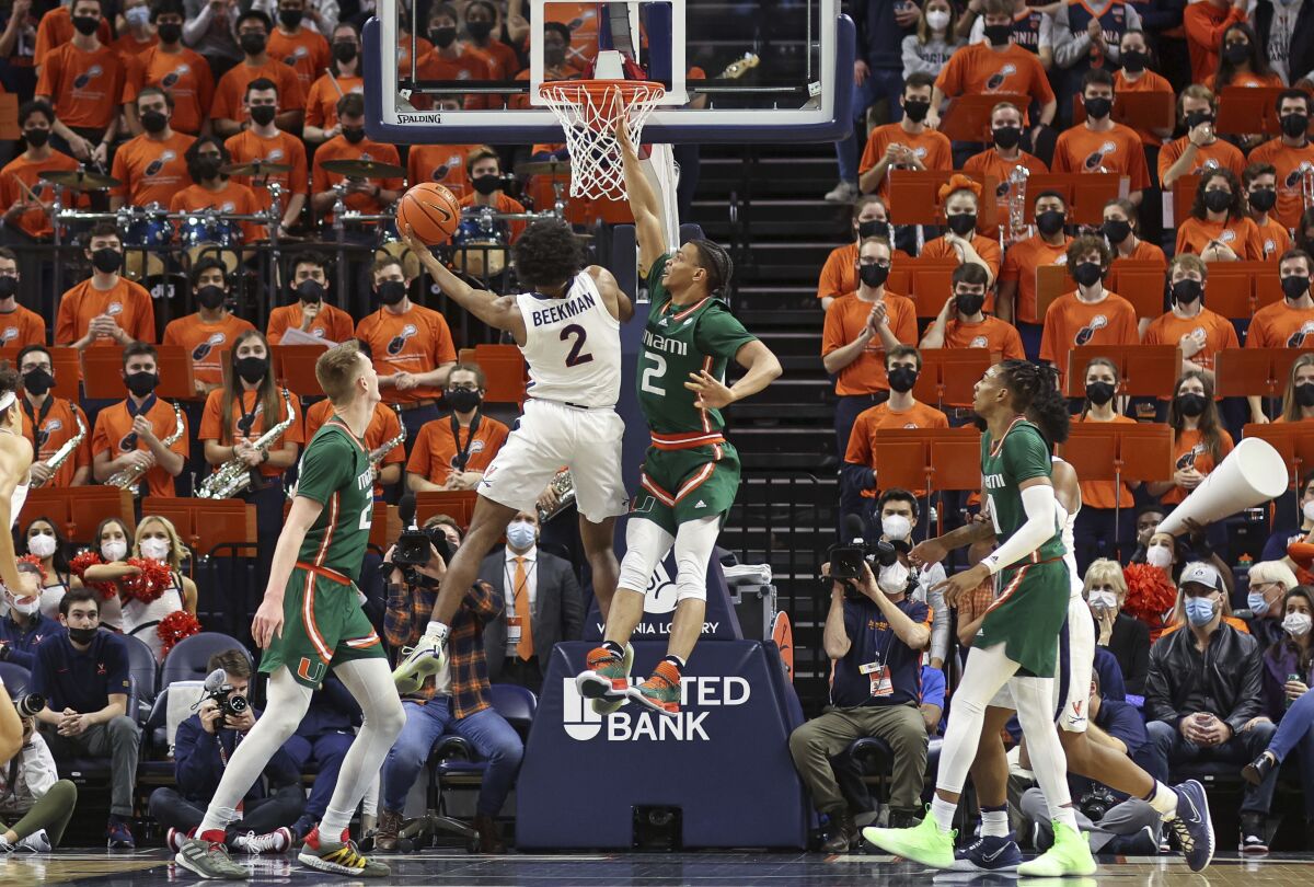 Virginia guard Reece Beekman (2) shoots as Miami guard Isaiah Wong (2) defends during an NCAA college basketball game in Charlottesville, Va., Saturday, Feb. 5, 2022. (AP Photo/Andrew Shurtleff)