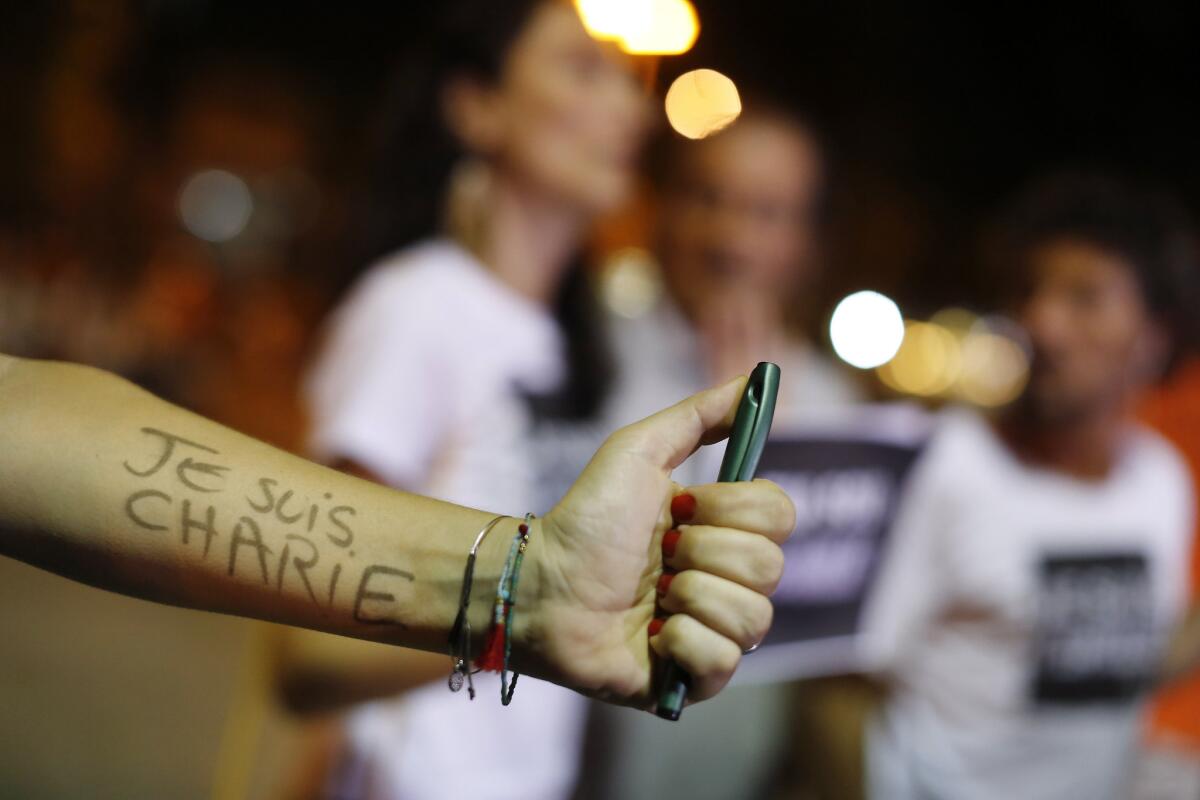 A woman holding a pen shows her arm covered with the words in French "I am Charlie" at a gathering in solidarity with those killed in an attack at the Paris offices of the weekly newspaper Charlie Hebdo, in a plaza in Rio de Janeiro, Wednesday, Jan. 7, 2015. Masked gunmen stormed the offices of the satirical newspaper that caricatured the Prophet Muhammad, killing 12 people Wednesday, including the editor, before escaping in a car. It was France's deadliest postwar terrorist attack. (AP Photo/Leo Correa)