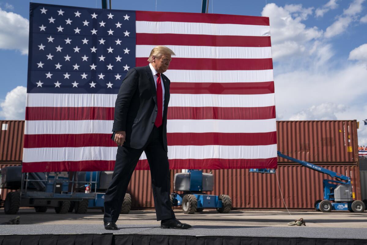 President Trump walks past a large U.S. flag before giving a speech at a shipbuilding firm in Marinette, Wis., on June 25.