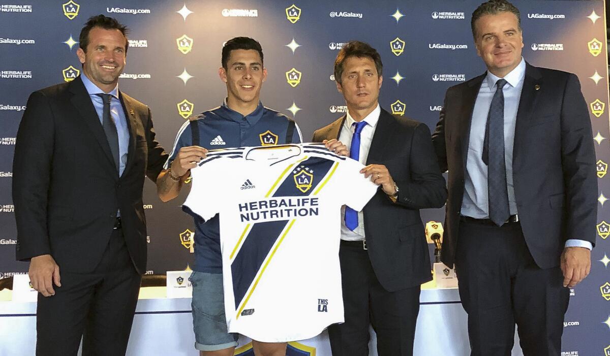 Forward Cristian Pavón is introduced by the Galaxy on Aug. 8 at Dignity Health Sports Park. He's joined by team president Chris Klein, left, head coach Guillermo Barros Schelotto and general manager Dennis te Kloese.