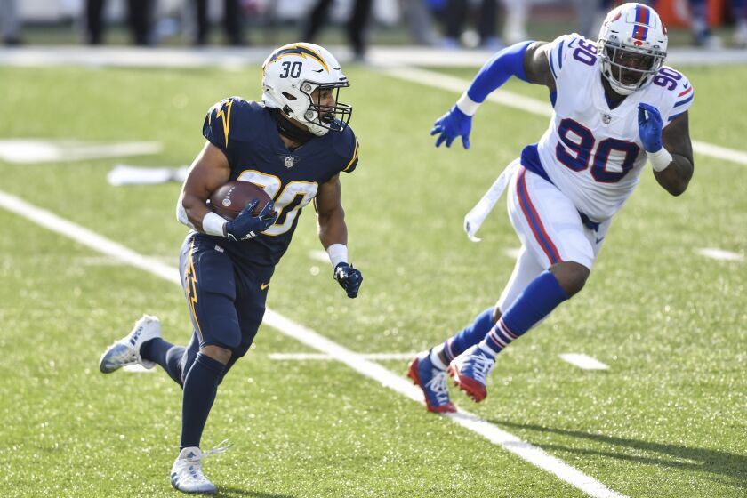 Los Angeles Chargers running back Austin Ekeler (30) runs the ball against Buffalo Bills defensive tackle Quinton Jefferson (90) during the first half of an NFL football game, Sunday, Nov. 29, 2020, in Orchard Park, N.Y. (AP Photo/Adrian Kraus)