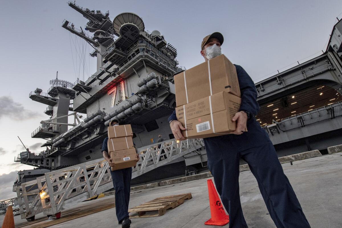 Sailors assigned to the Theodore Roosevelt move ready-to-eat meals for sailors being taken off the ship to hotels in Guam on April 10.