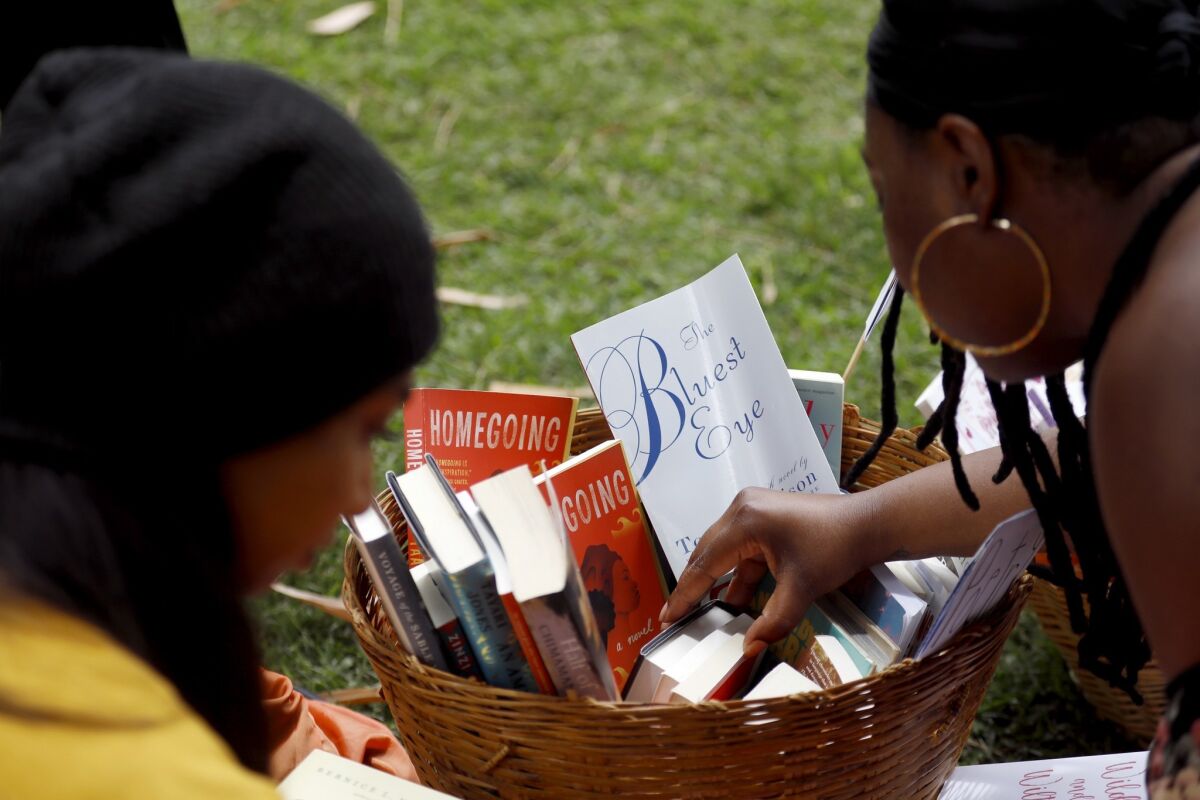 Guests reach into a basket of books by black female authors, at a Free Black Women's Library event outside the Huntington Library.