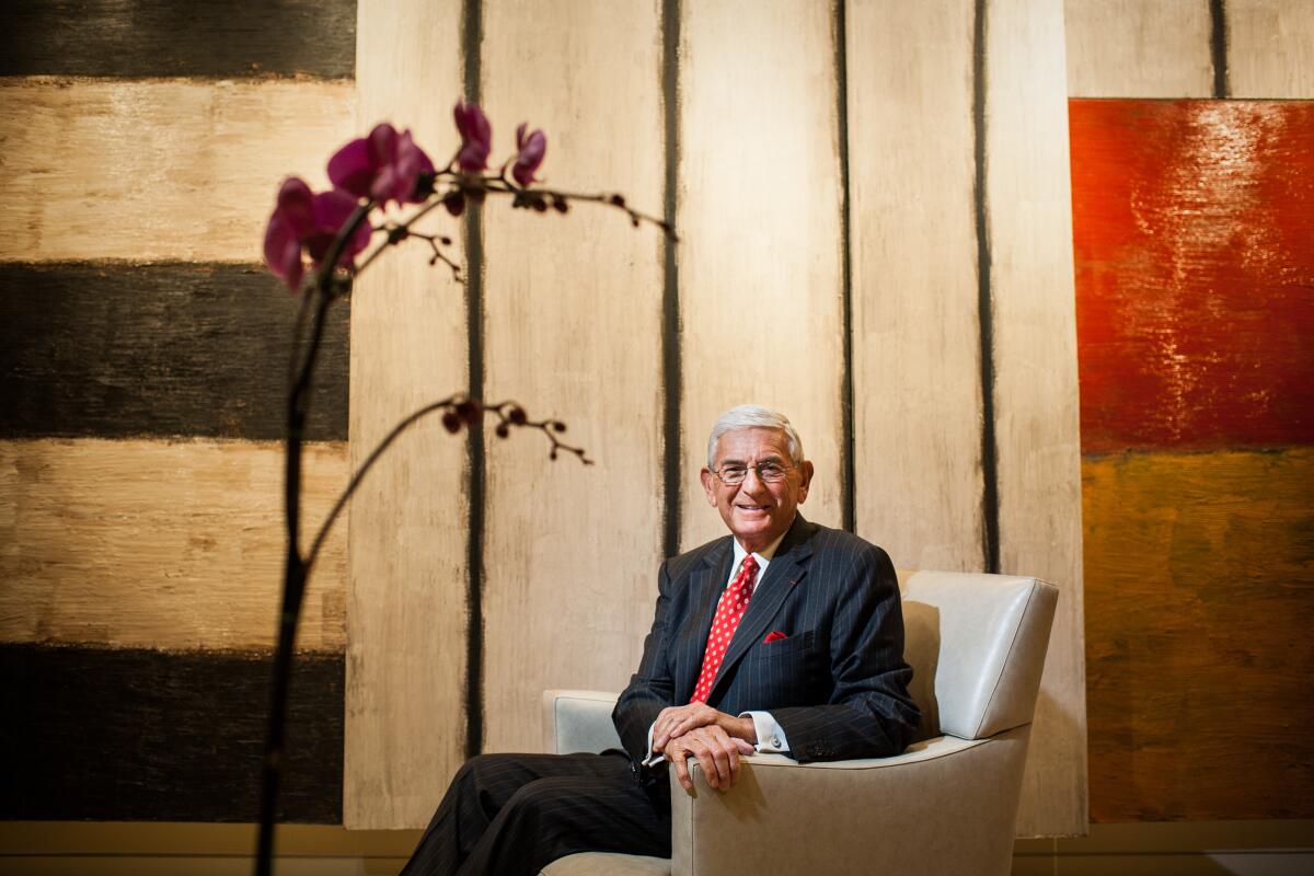 Eli Broad sits in a chair in front of an artwork