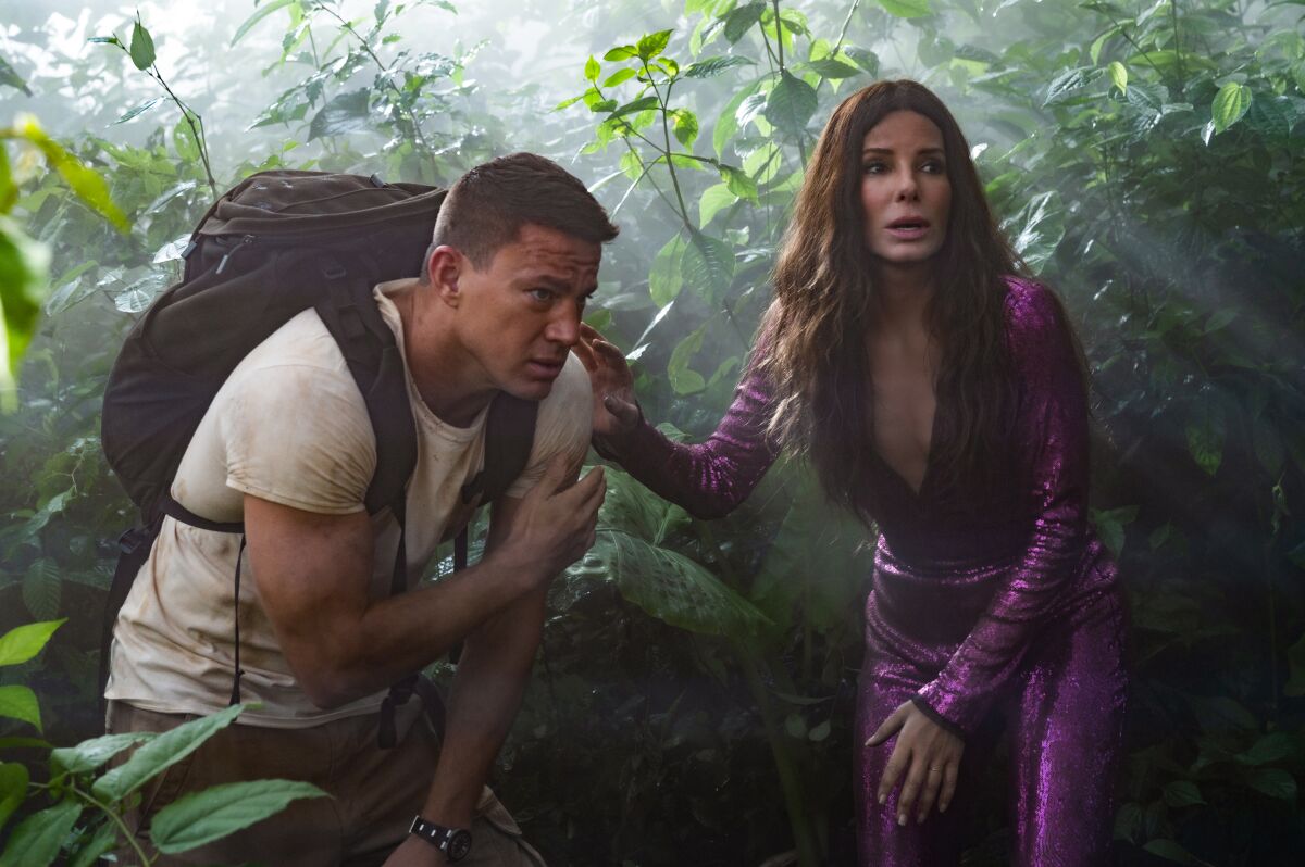 A man wearing a backpack and a woman in a purple sequined jumpsuit in the movie “The Lost City.”