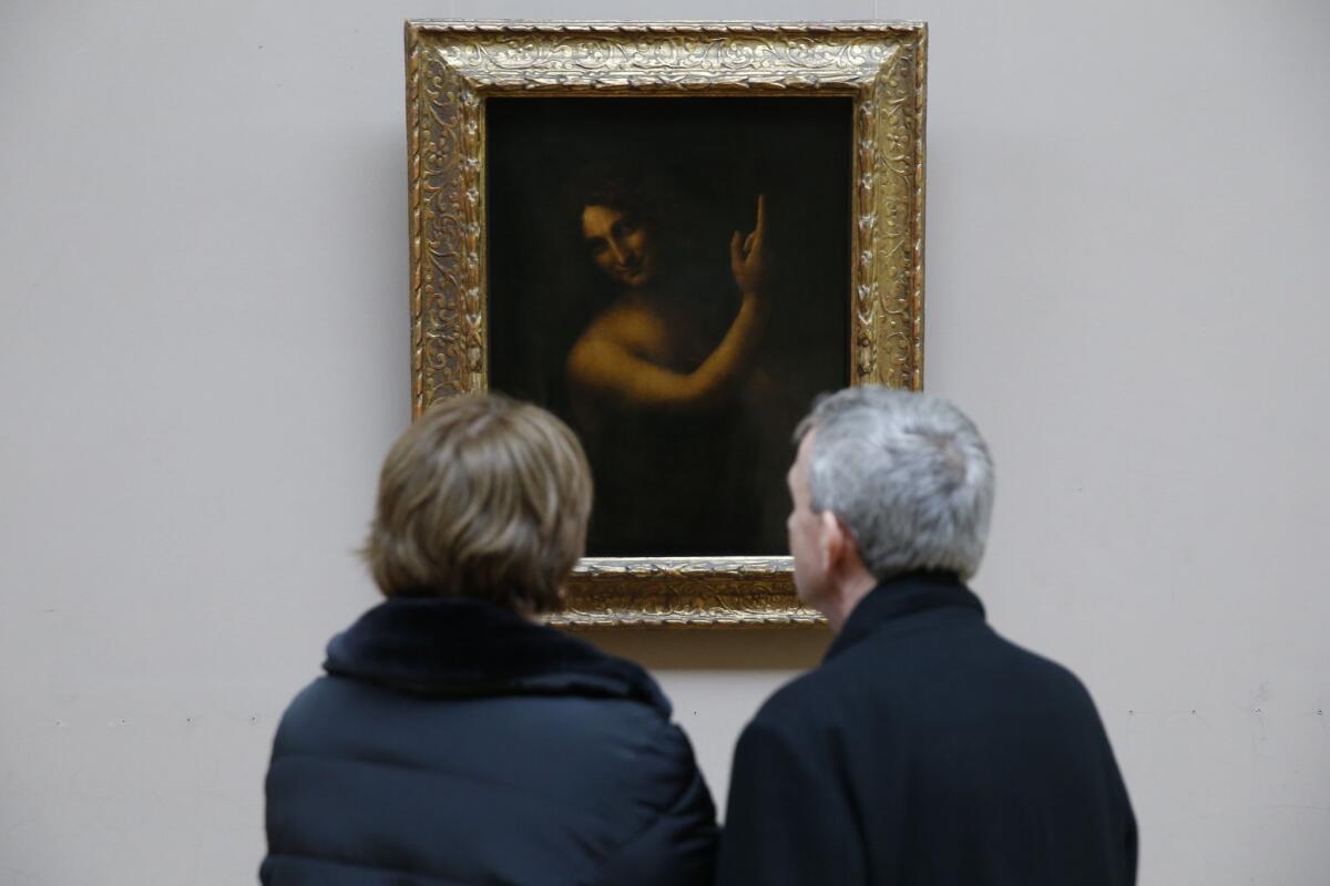 People look at the painting "Saint-Jean Baptiste" by Leonardo da Vinci in the Louvre Museum in Paris. The picture is about to be restored by lightening its layers of varnish.