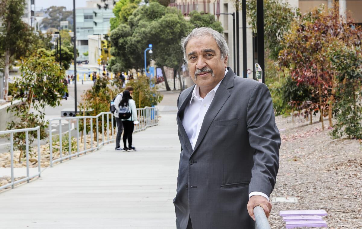 UC San Diego Chancellor Pradeep Khosla is wearing a suit while standing next to a railing.