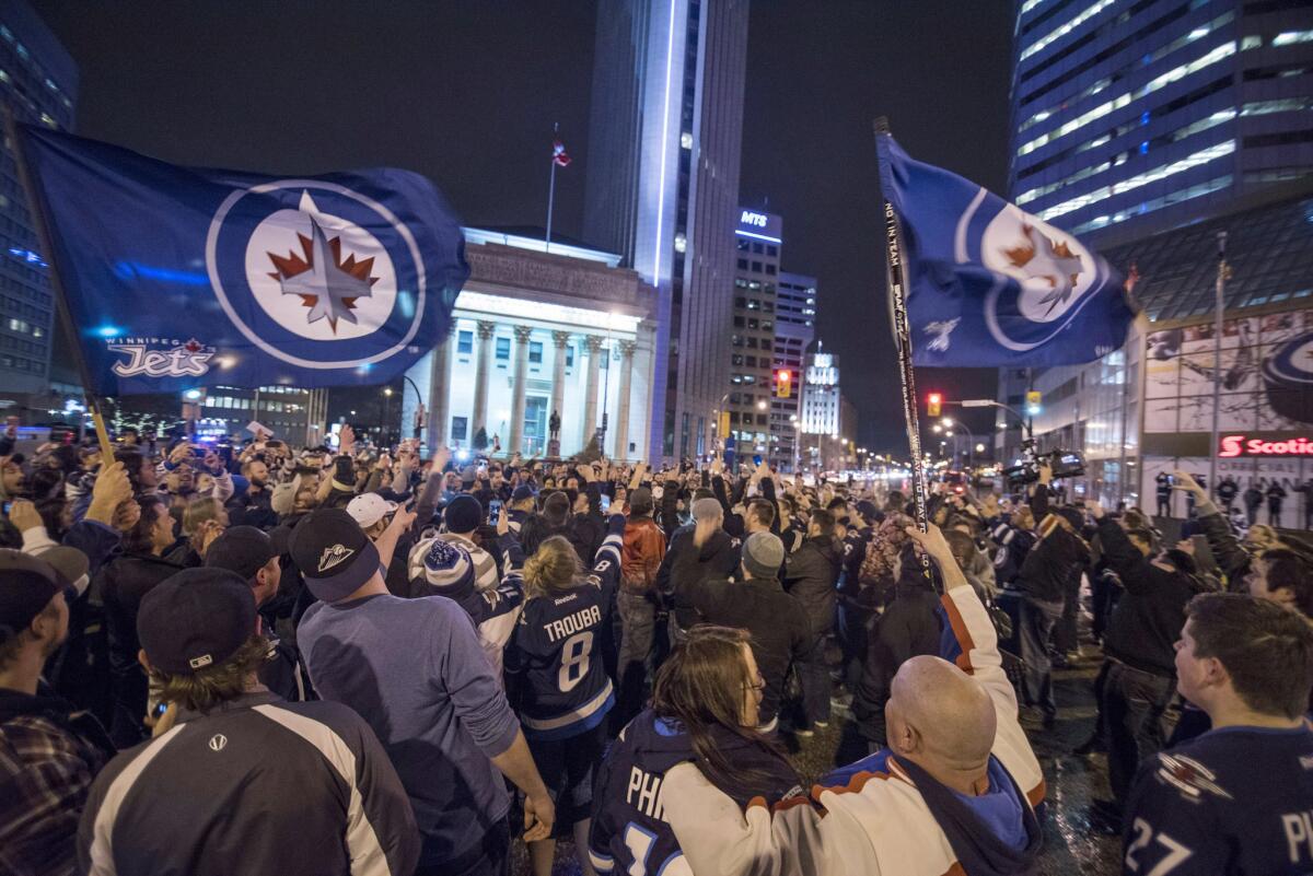 Hockey fans gather at the intersection of Main Street and Portage Avenue in Winnipeg to celebrate the Jets clinching a playoff spot on April 9.