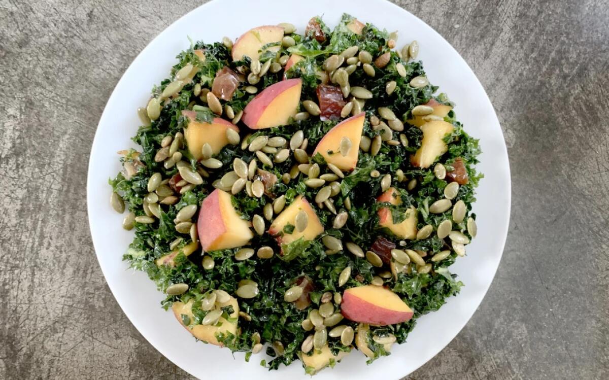 Kale, pepitas and sliced peaches on a plate.