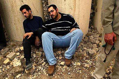 Two Iraqi men sit in despair amid homes, shops and restaurants that were destroyed by allied bombing on the Mansour neighborhood earlier Monday.
