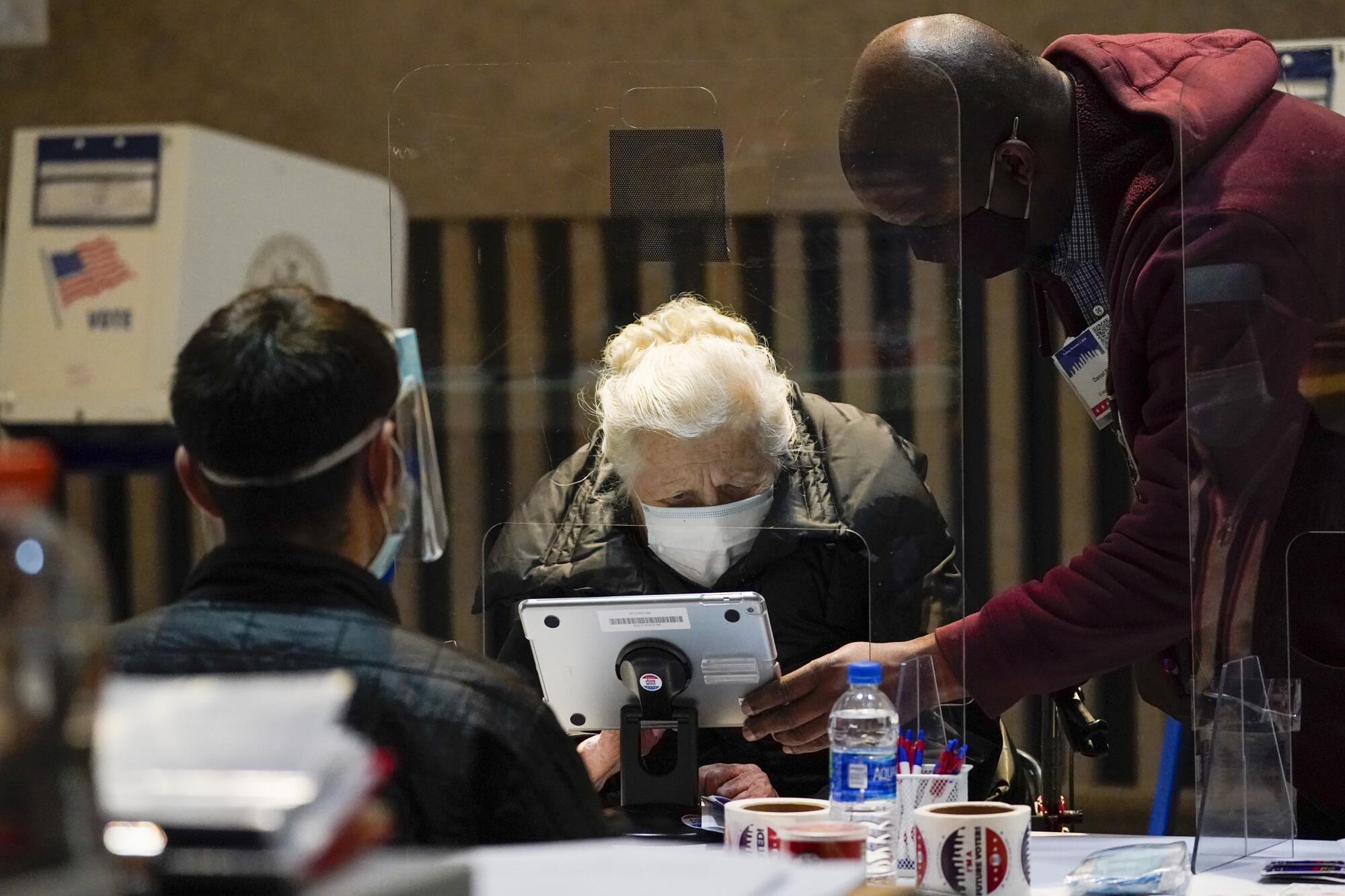 Trabajadores electorales ayudan a una persona mayor a firmar para votar el día de las elecciones en Nueva York.