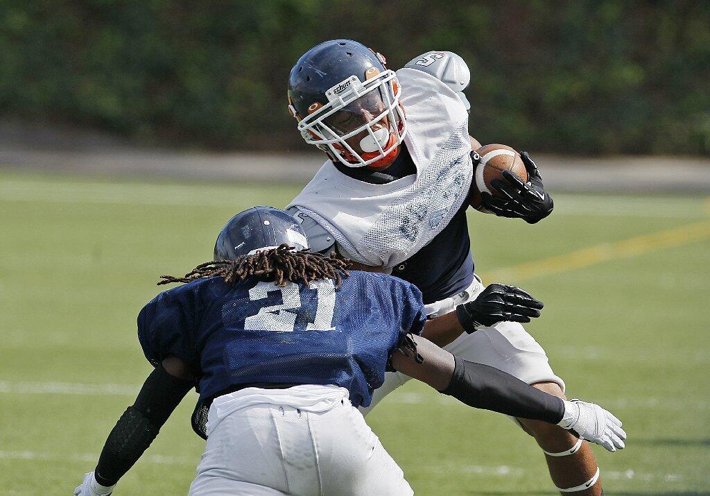 Orange Coast College's Stan Johnson is tackled by De Andre Dickerson during an intrasquad scrimmage on Saturday.
