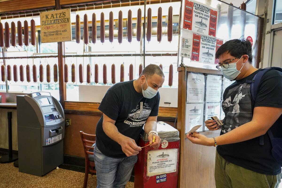 ARCHIVO —  un empleado de Katz's Deli (a la izquierda) revisa el certificado de vacunación contra el COVID-19