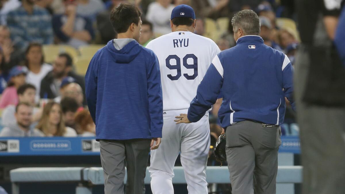 Starting pitcher Hyun-Jin Ryu walks off the field with Dodger trainers in the third inning of Saturday's game against the San Francisco Giants. Ryu was hurt fielding a ground ball and had to leave the game.