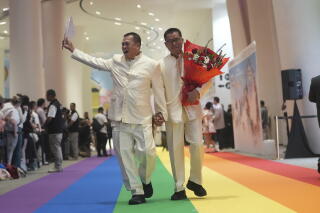 A just-married gay couple walking on a rainbow carpet in Bangkok