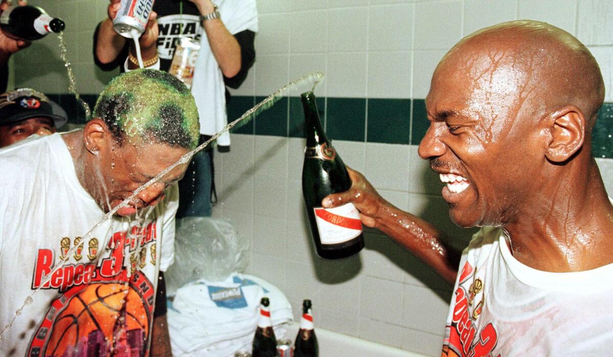 SALT LAKE CITY, UNITED STATES: Dennis Rodman (L) of the Chicago Bulls gets beer and champagne poured on his head by teammate Michael Jordan (R) and others 14 June after winning game six of the NBA Finals against the Utah Jazz at the Delta Center in Salt Lake City, UT. The Bulls won the game 87-86 to take their sixth NBA Championship. AFP PHOTO/Mike NELSON (Photo credit should read MIKE NELSON/AFP via Getty Images)