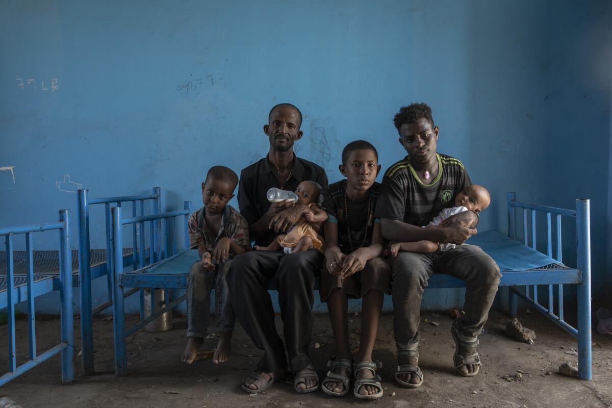Tigrayan refugee Abraha Kinfe Gebremariam, 40, second from left, and his family sit on a bed at a shelter in Sudan