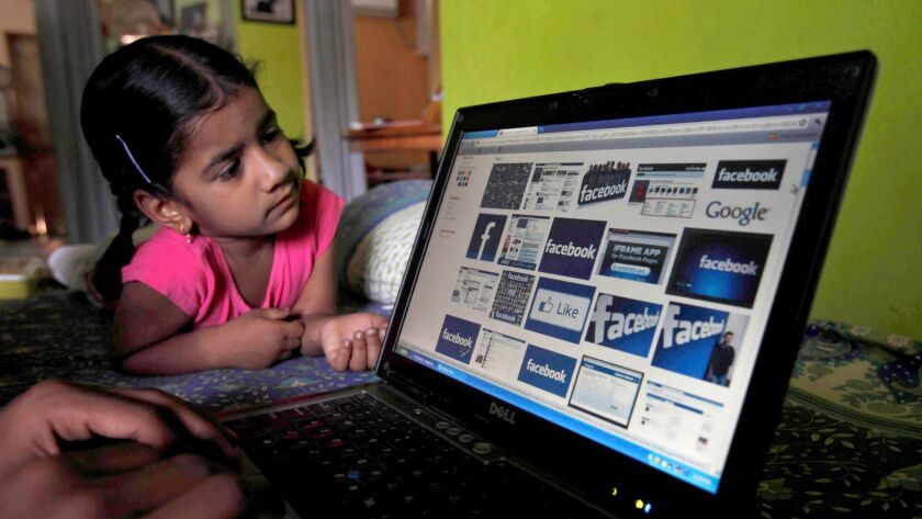 A child looks at a laptop displaying Facebook logos in May of 2012.