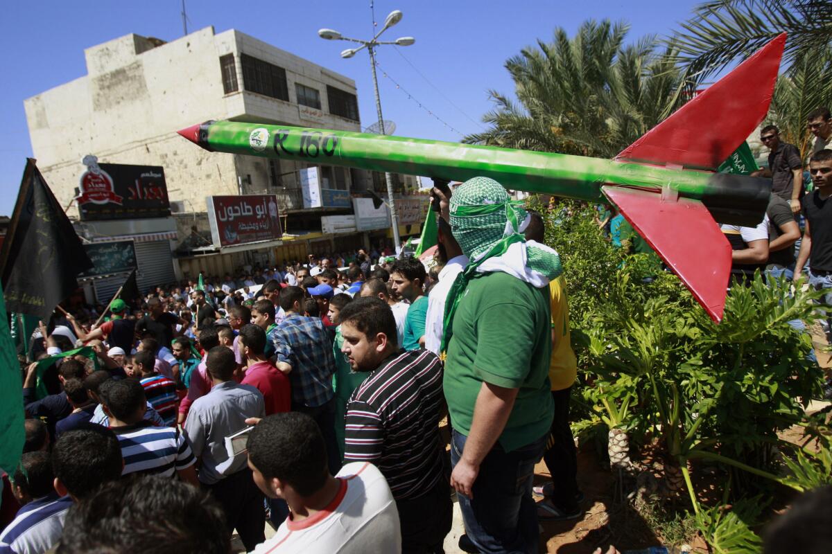 A supporter of the militant group Hamas holds a mock rocket as others shout slogans against the Israeli offensive in the Gaza Strip, during a protest Friday in the West Bank town of Tulkarm.