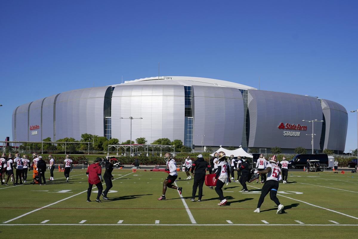 The San Francisco 49ers defensive players runs drills during practice in front of State Farm Stadium.