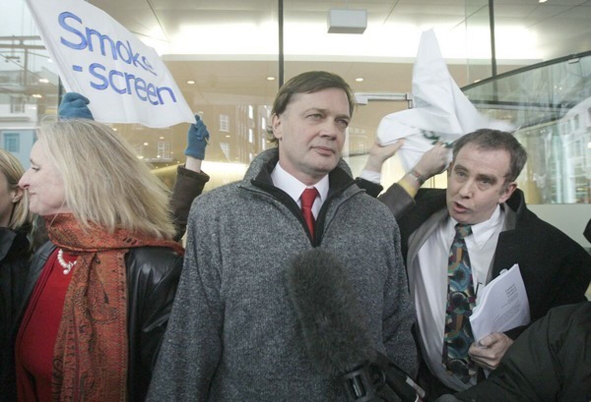 Discredited scientist Andrew Wakefield is show between his wife and a reporter.  