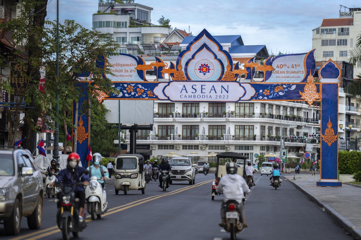 Commuters drive as a gate of the upcoming Association of Southeast Asian Nations (ASEAN) summit puts on a road in Phnom Penh, Cambodia, Thursday, Nov. 10, 2022. Southeast Asian leaders hold meetings with various groups ahead of the summit opening on Friday. (AP Photo/Anupam Nath)