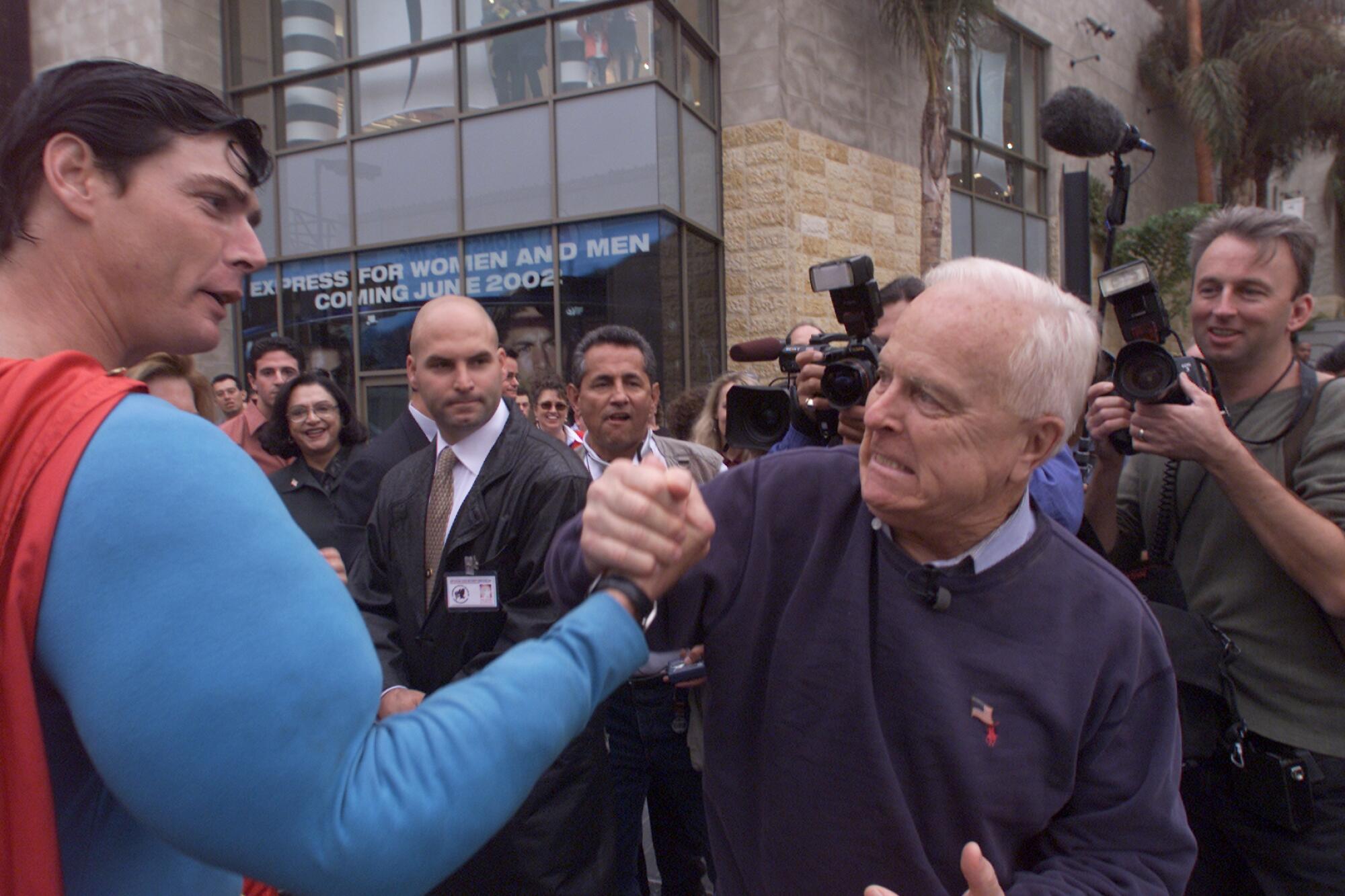 Richard Riordan pretends to arm wrestle with a man dressed in a Superman suit